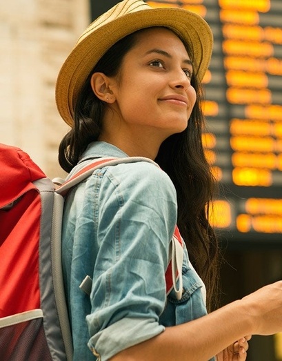Female traveler ready for adventure near travel info screen.